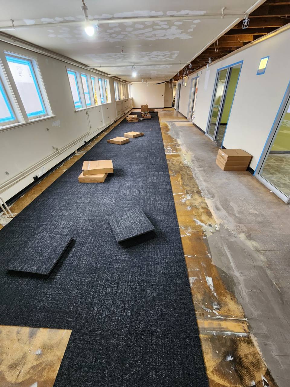 Before: corridor mid-installation with carpet tiles being laid