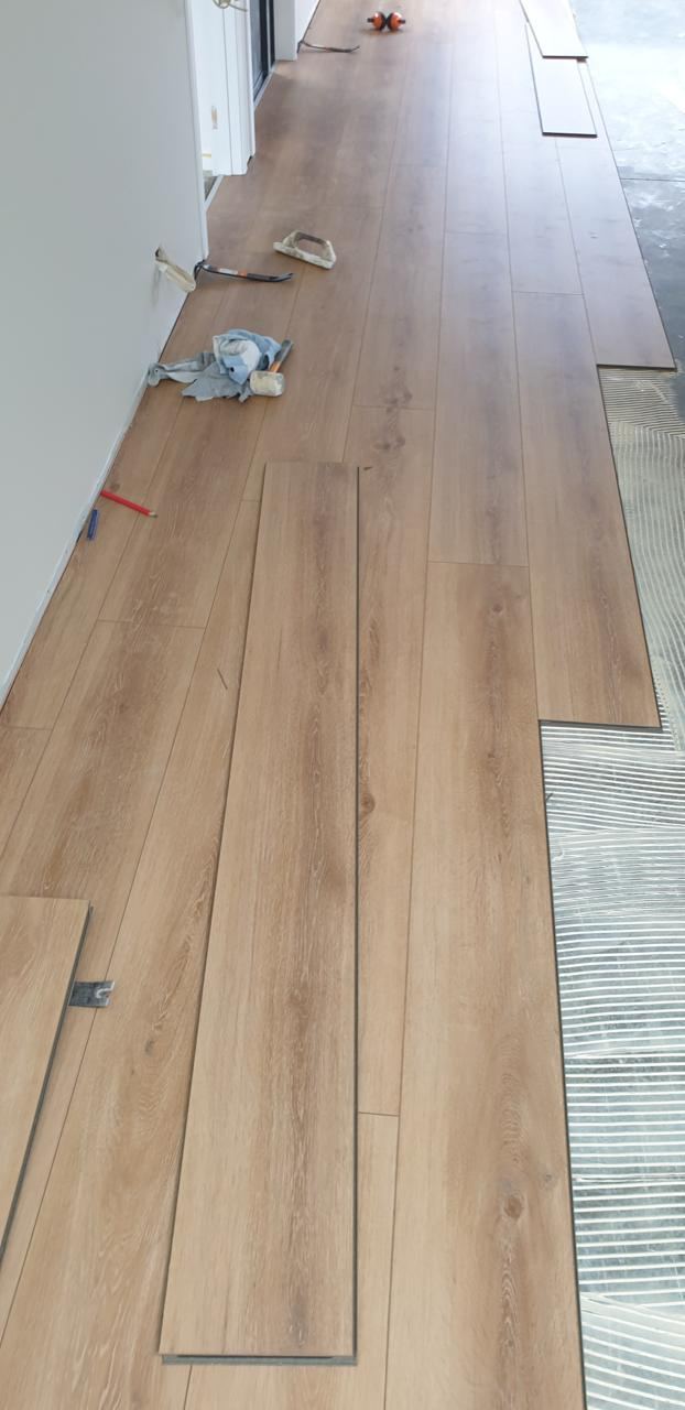 Before: bare subfloor with planks stacked ready to lay