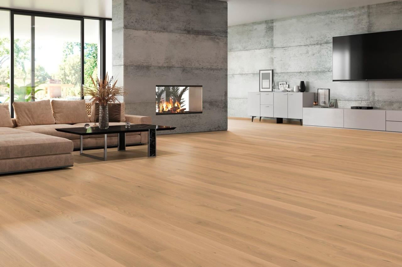 Wide-plank oak flooring installed through an open-plan living room with a concrete fireplace